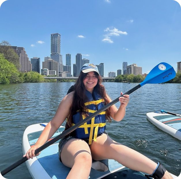 Isa paddle boarding on Lady Bird Lake with the Austin skyline behind her